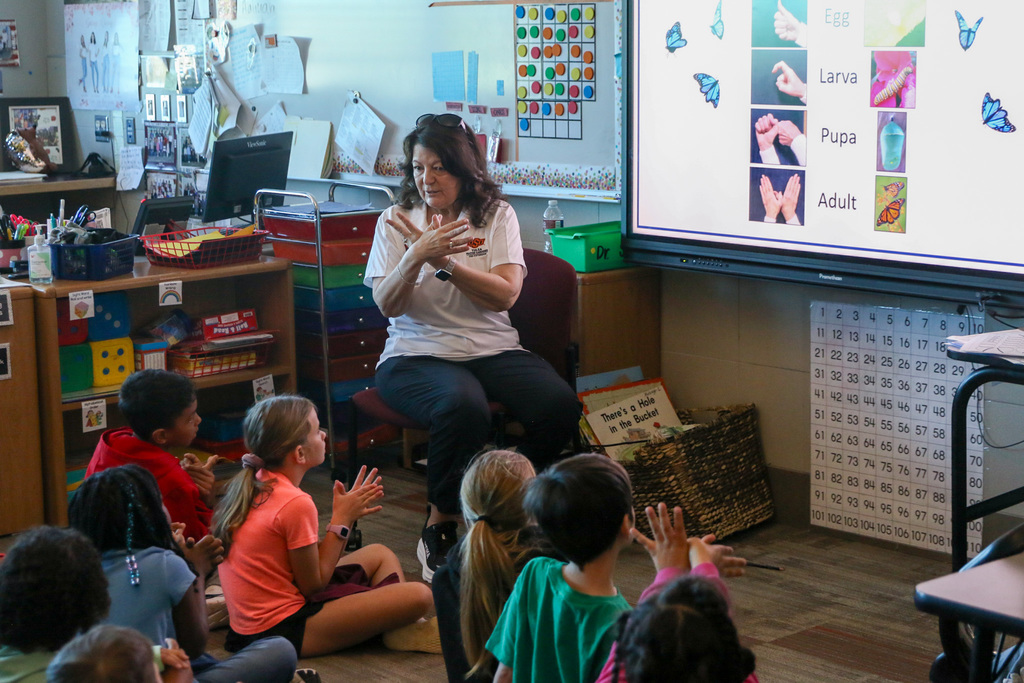 Oklahoma State Master Gardener showing the hand signs of the life stages of a butterfly.