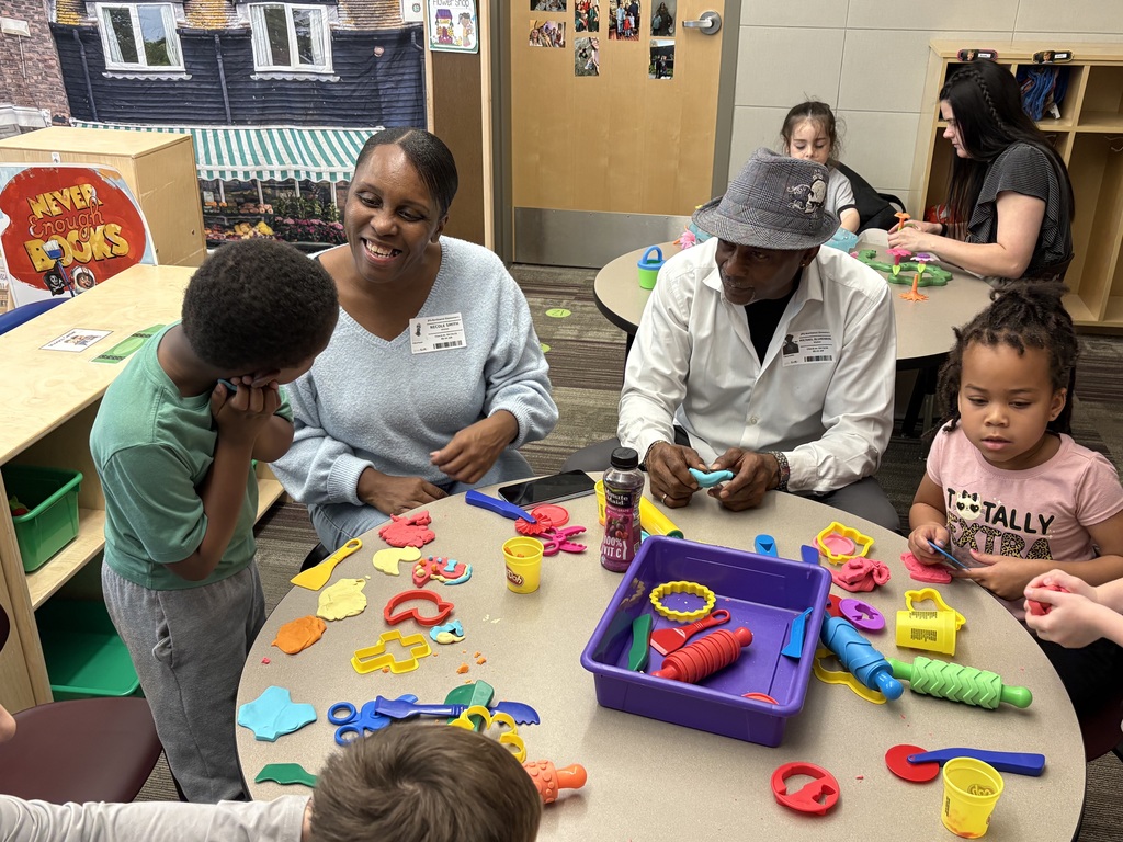 Senior living residents at table with Pre-K students working with playdoh