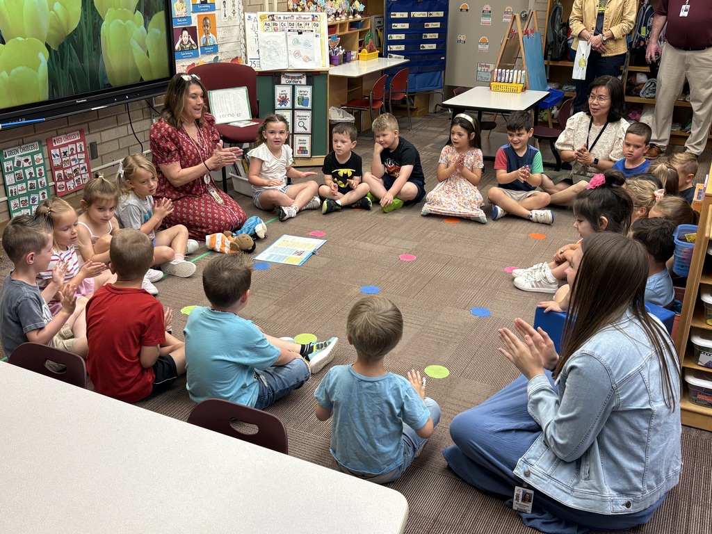 Pre-K students sitting in a circle with teacher and singing a song