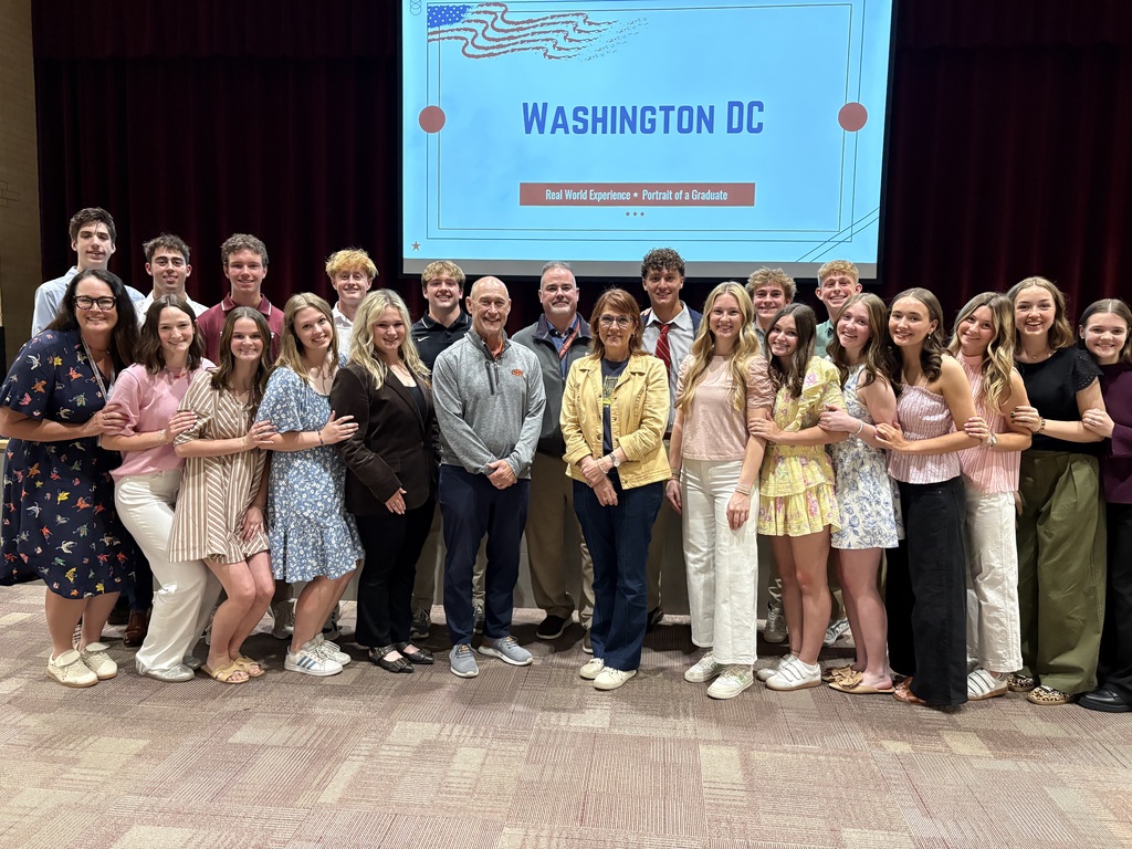 Group of high school student council members standing near stage with three JPS Board members after presenting about their recent trip to Washington D.C.