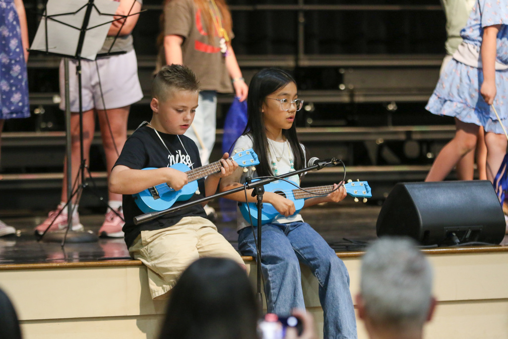 a boy and a girl playing ukuleles