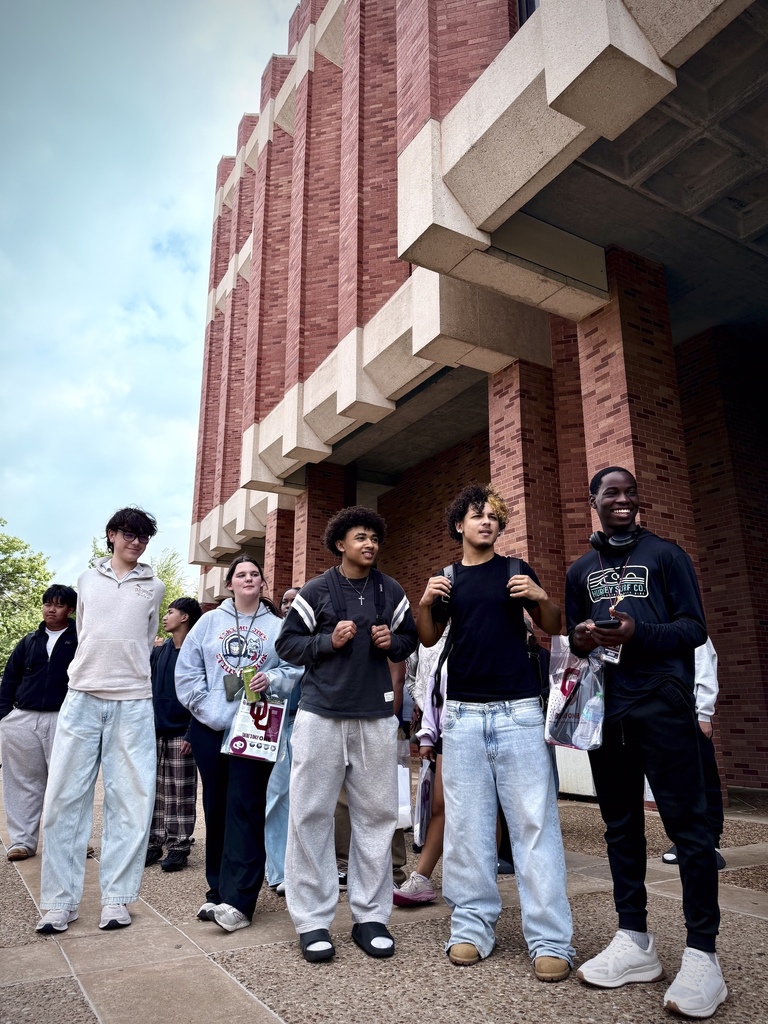 Group of students standing and smiling near academic building at University of Oklahoma