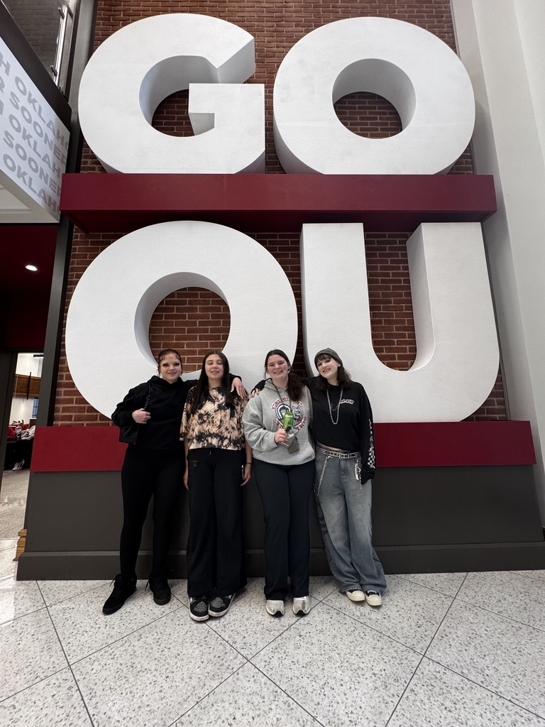 Group of four female high school students standing in front of "Go OU" letters on campus of the University of Oklahoma
