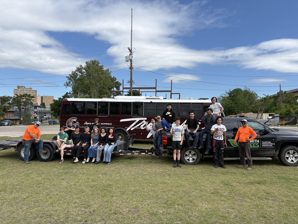 A group of students and workers in front of the school bus and Up with Trees Truck