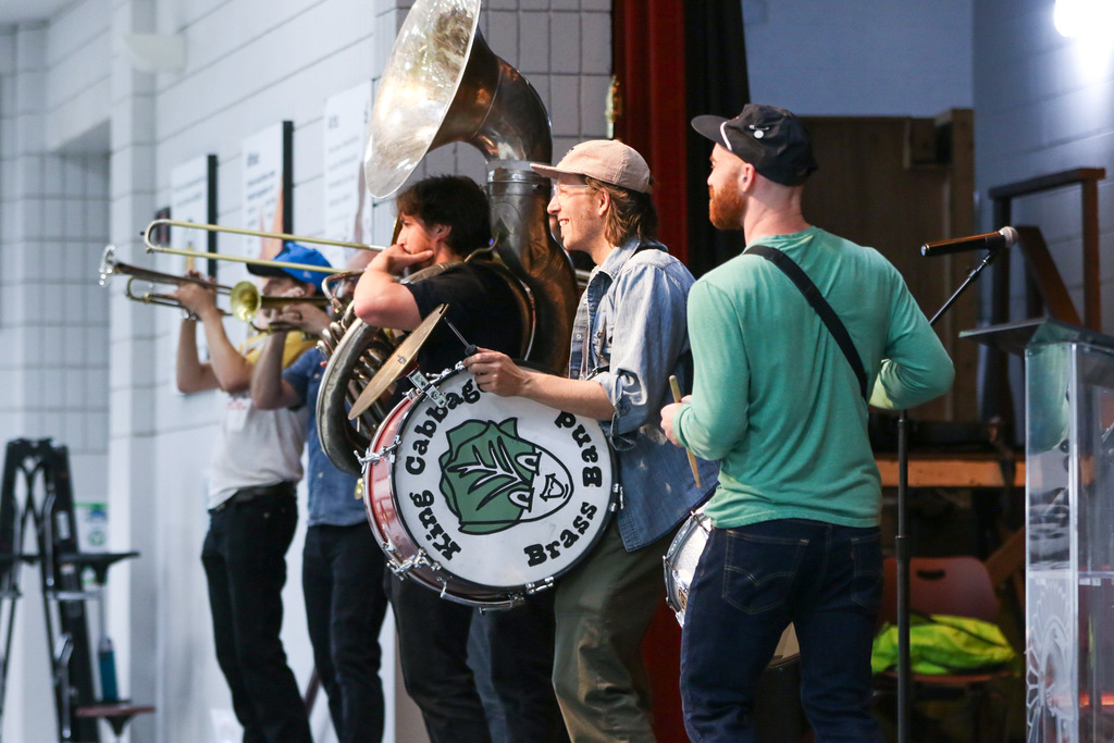 view from the side of the stage of the band playing. on the side of the drum is an image of a cabbage and it says king cabbage brass band.