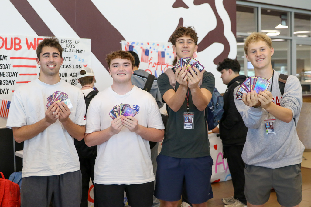four boys holding up their decks of teacher traiding cards