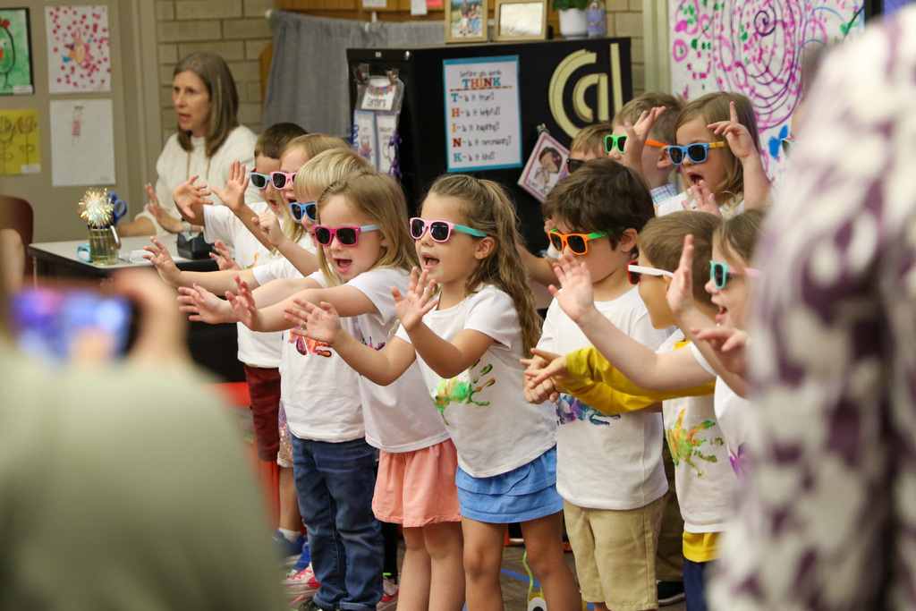 pre-k students wearing sunglasses doing a song and dance for their parents.