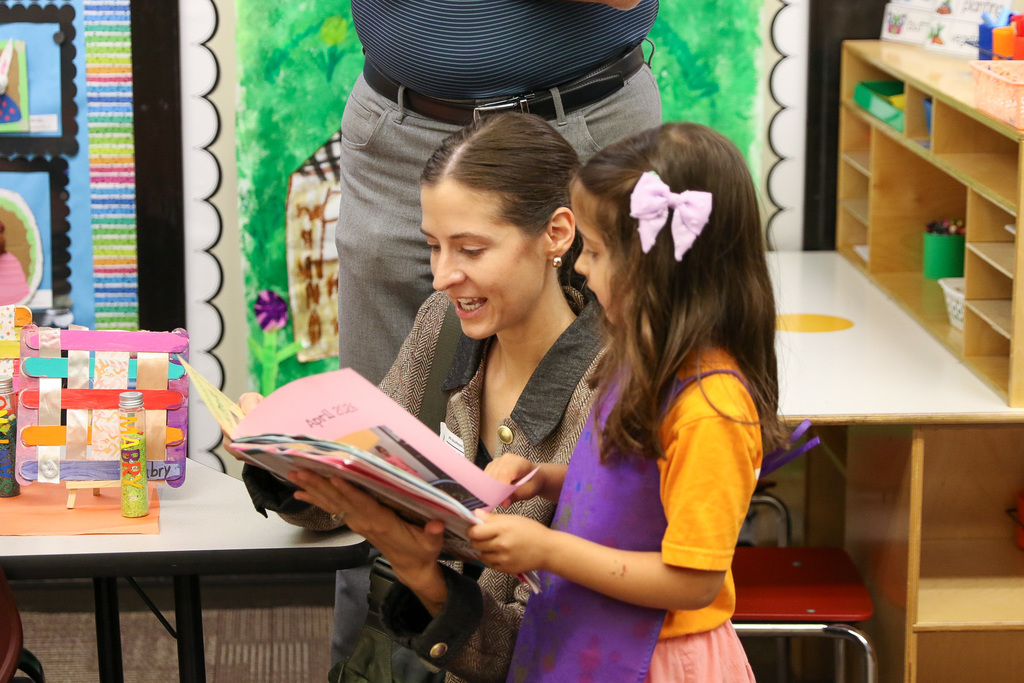 mom and daughter going through a book with photos of her throughout the school year