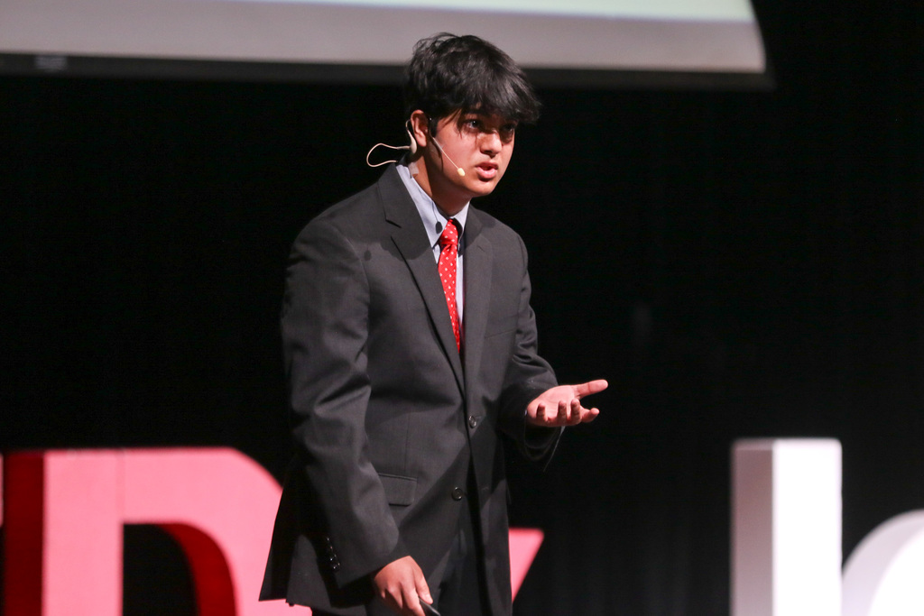 close up shot of a student on stage with a hand up