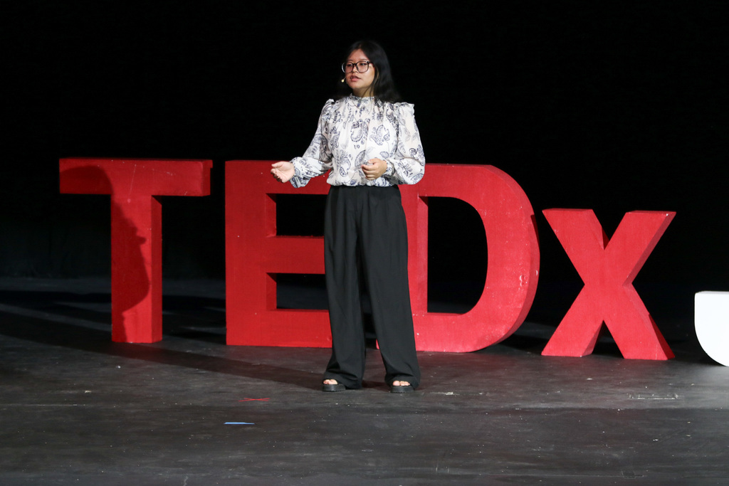 student in front of the Tedx sign on stage