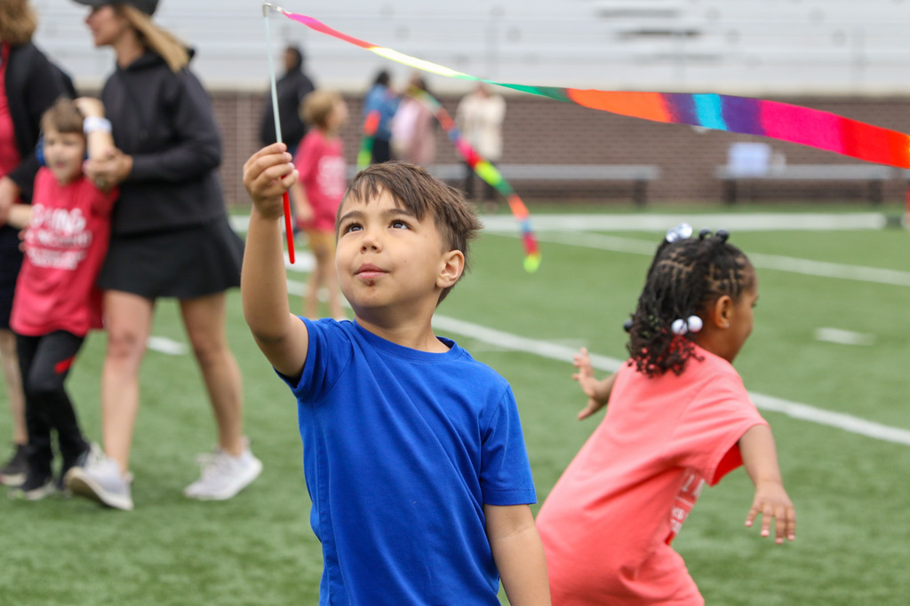 boy with a streamer in his hand. he holds it high with it blowing in the wind