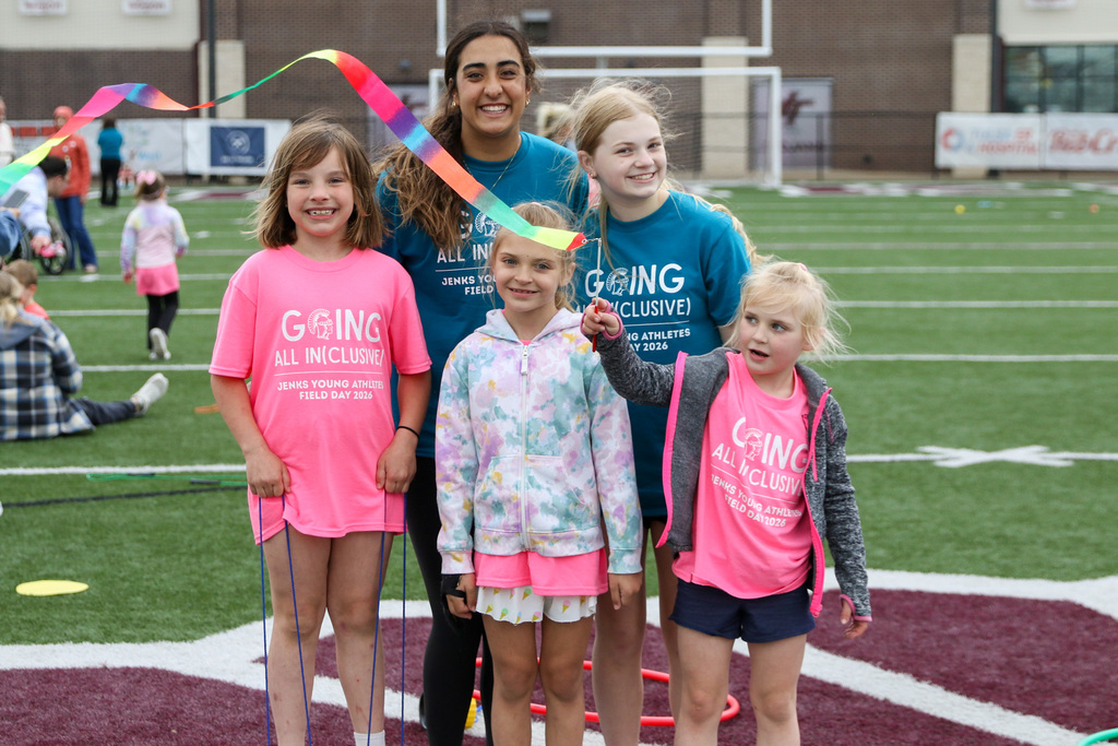two high school volunteers posing for a photo with three student athletes