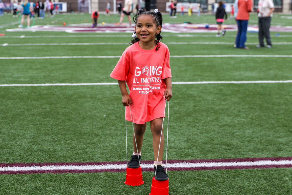 student athlete walking with little cup stilts on her feet.