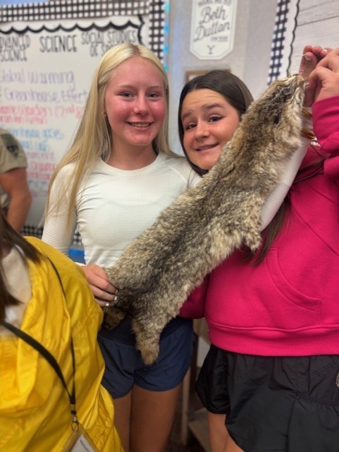 2 students holding animal pelt