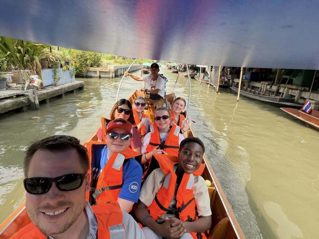 students on a boat at a market in thialand