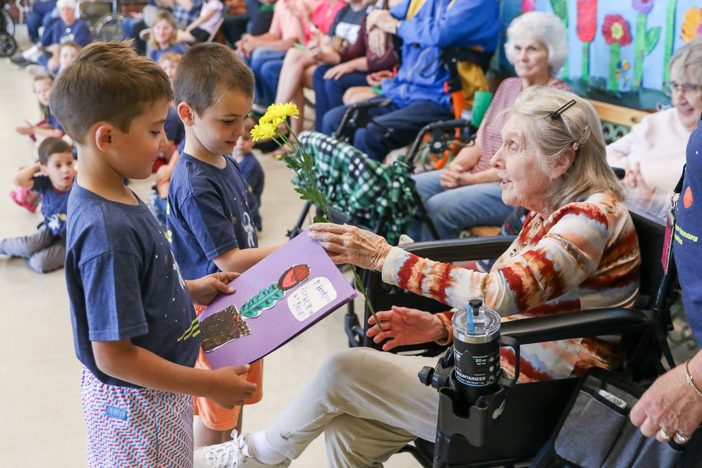 two boys giving a grandma a handmade note and flowers