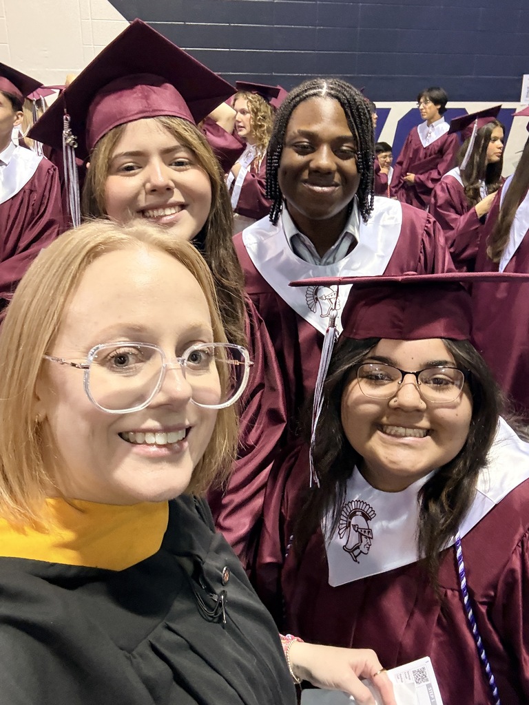 A group of students with a staff member in graduation gear