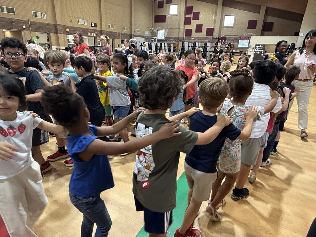 Kindergarten students form a long conga line as they dance around the celebration