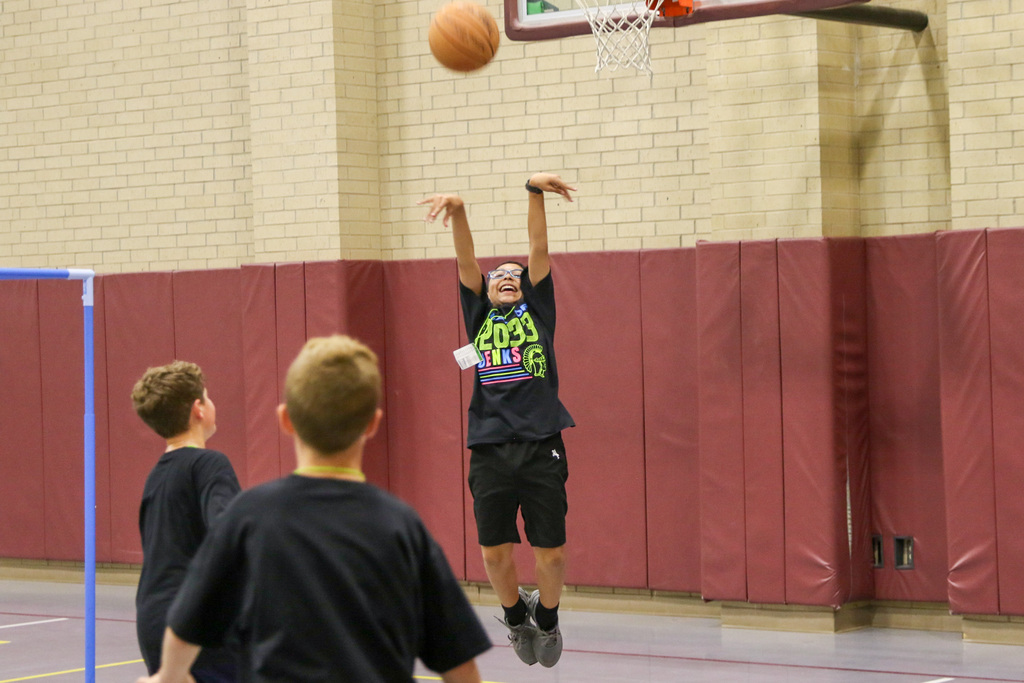 boy shooting the ball with a smile on his face. he is mid air. 