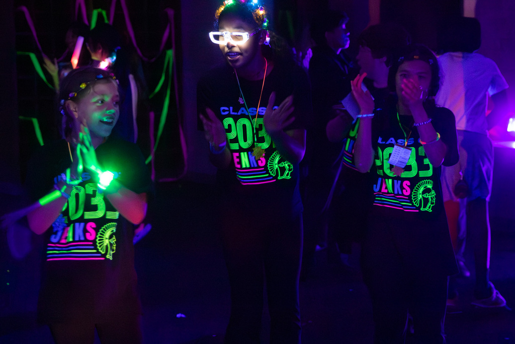3 girls in glow in the light up bracelets and glasses dancing to the cha cha slide in the glow in the dark room