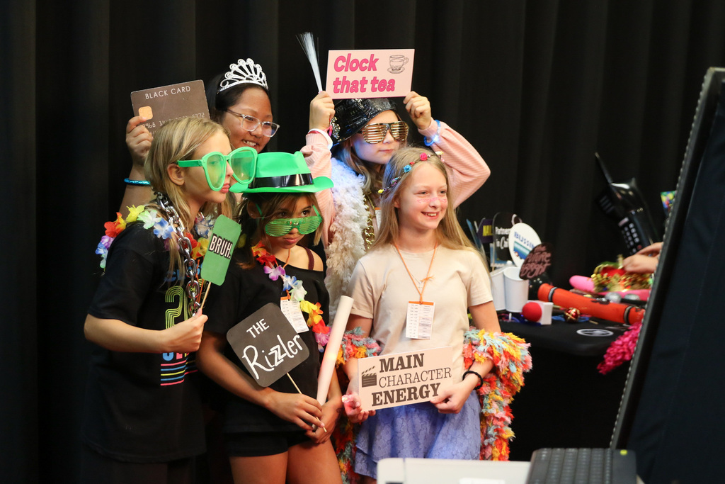 5 girls wearing funny hats and large glasses posing for a photo in the photo booth