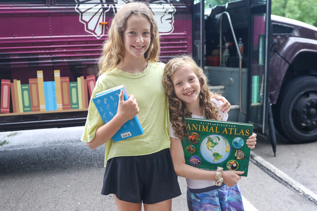 two girls posing outside the bookmobile with their books they chose