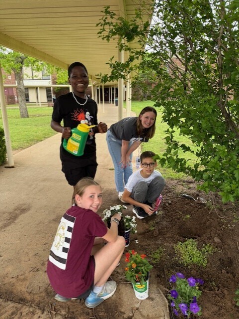Students planting flowers in front of school