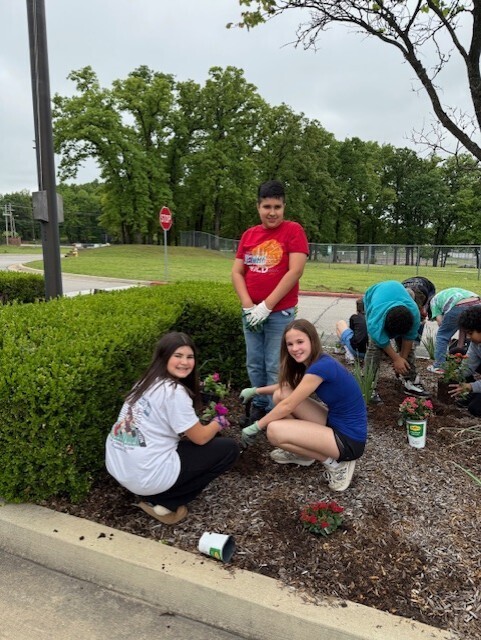 students planting flowers in front of school