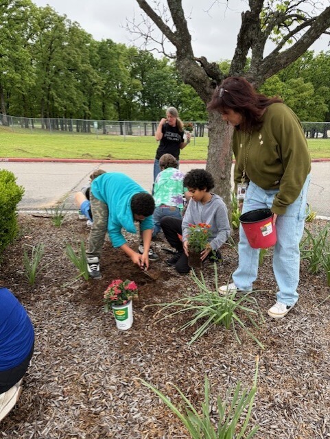 students planting flowers in front of school