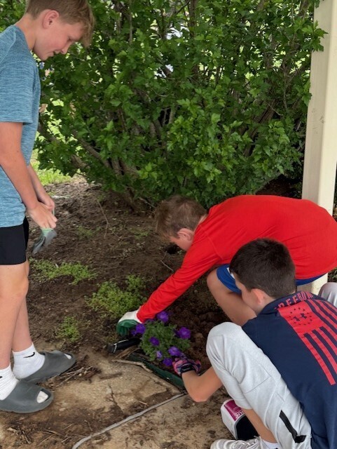 students planting flowers in front of school