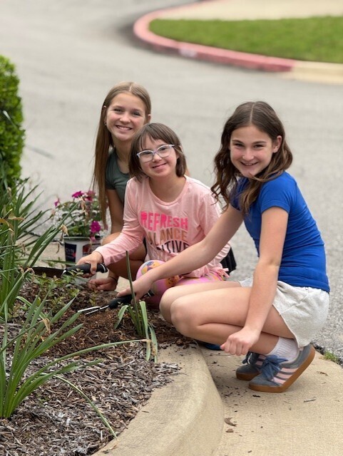 students planting flowers in front of school