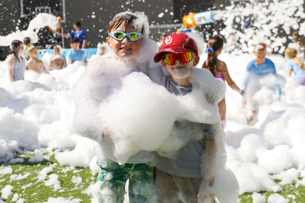 two boys one wearing swim goggles and the other a hat and sunglasses covered in foam