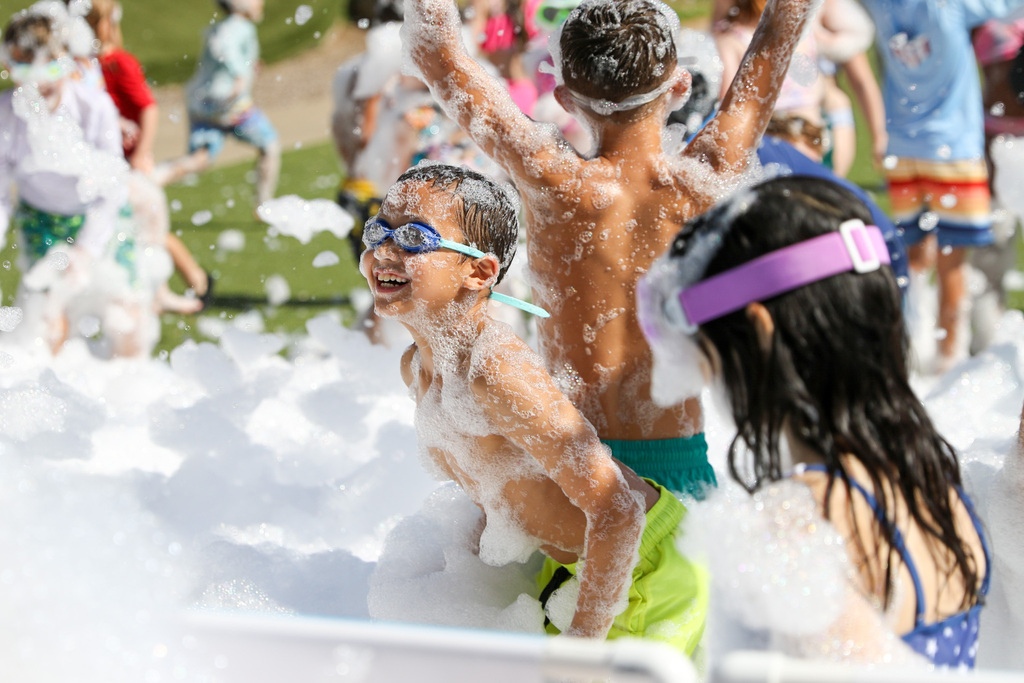 boy smiling with swim goggles on playing in the foam