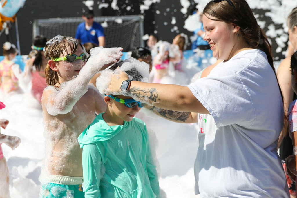 staff member and a student is putting foam on another student's head