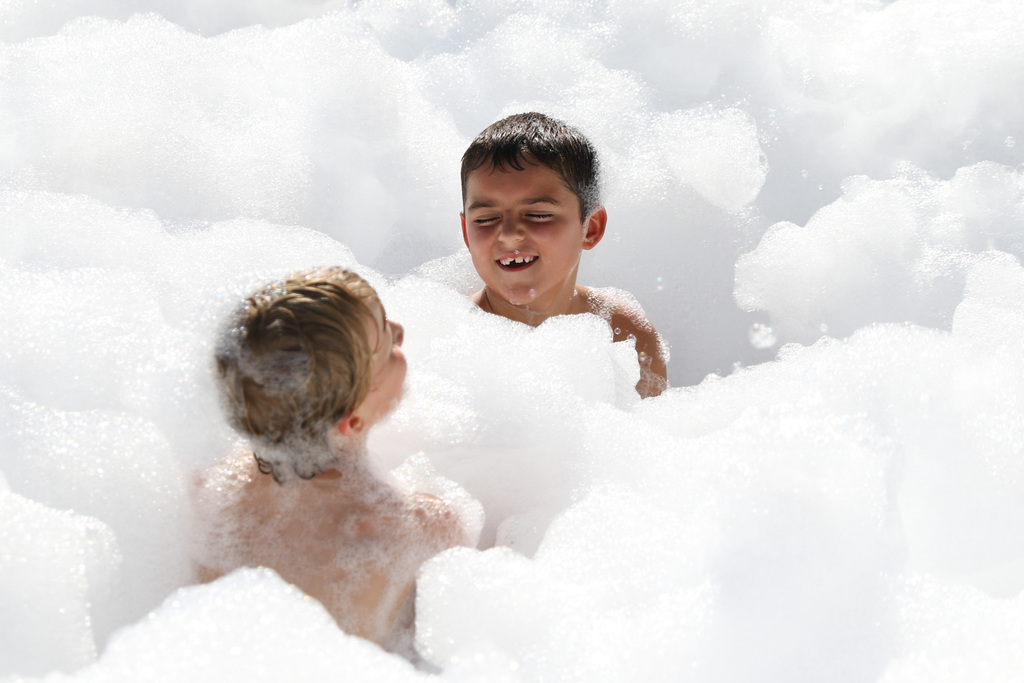 two boys sitting down in the foam. one boy facing the camera is smiling