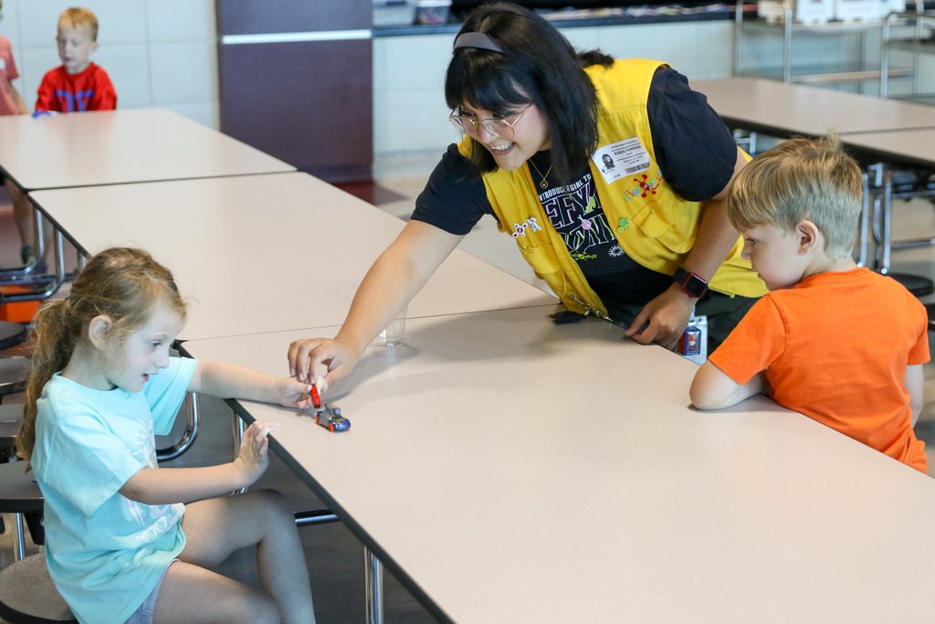 discovery lab staff member assisting a girl with pushing a car with a magnet