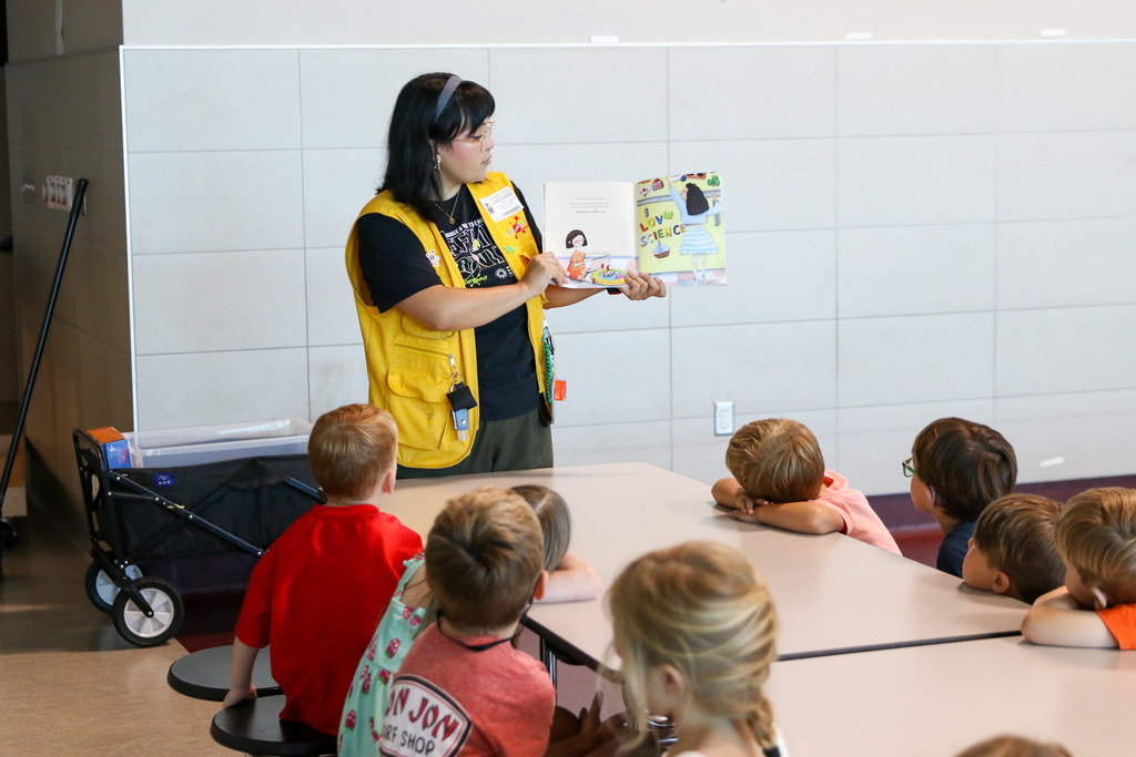 Discovery Lab employee reading a book to students about forces.
