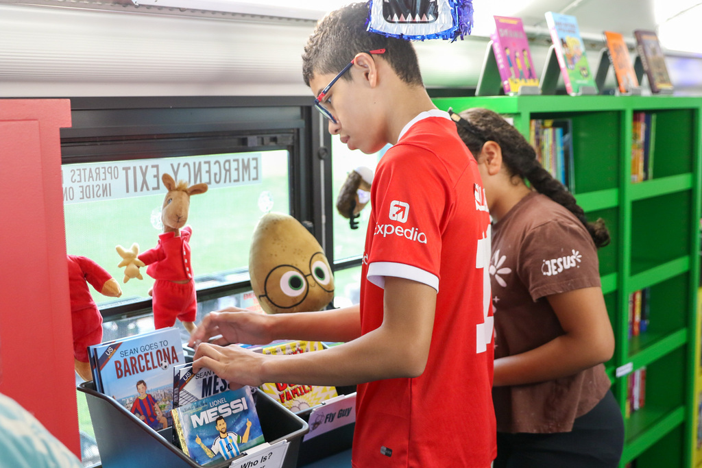 boy with a soccer jersey on looking through books about famous soccer players