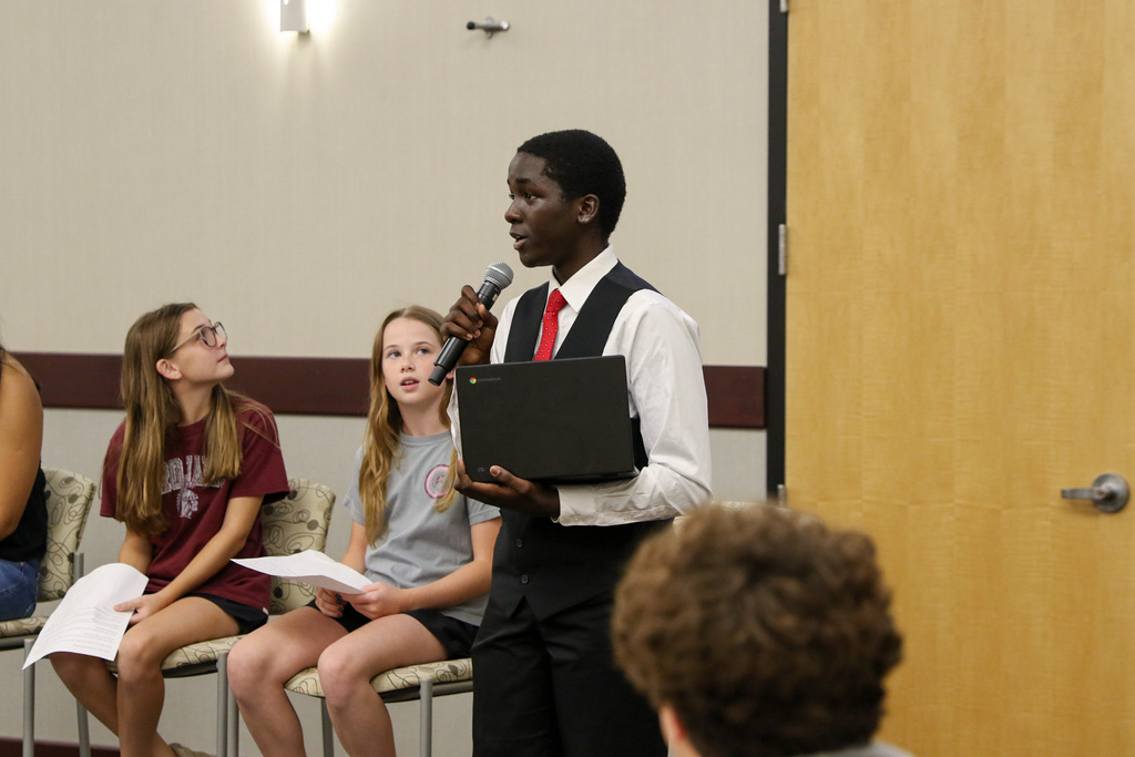 boy standing taking into a microphone giving his perspective on a portrait of a graduate attribute