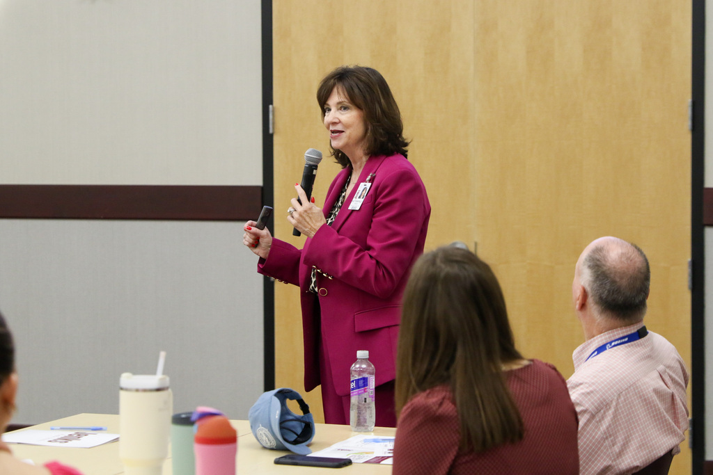 dr. butterfield standing and speaking into a microphone talking to the new teachers