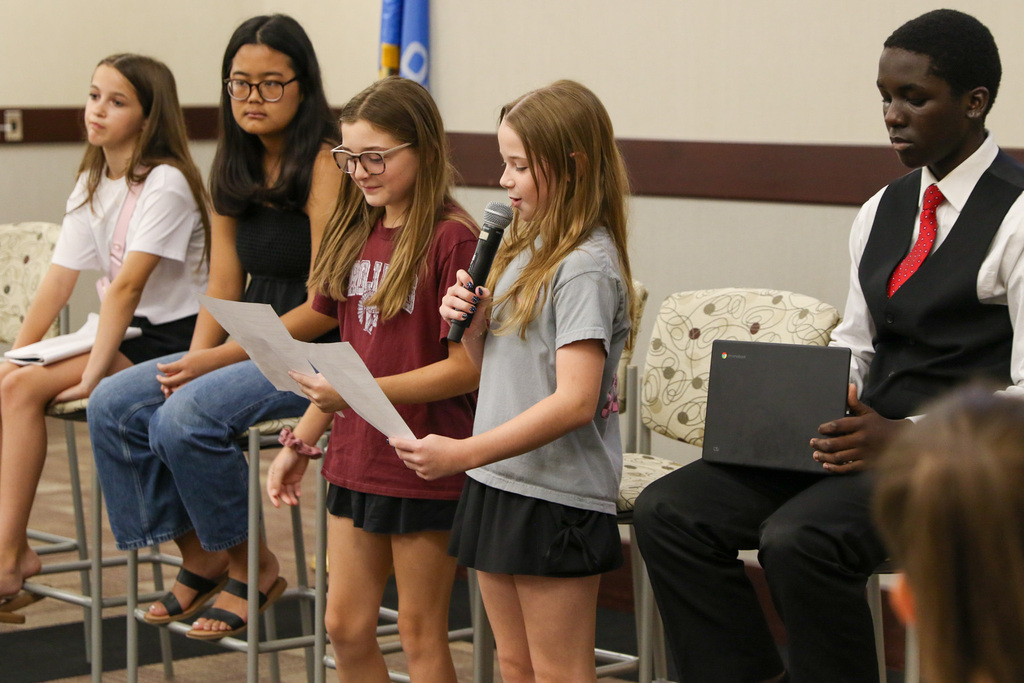 two girls standing and talking into a microphone giving their perspective on a portrait of a graduate attribute