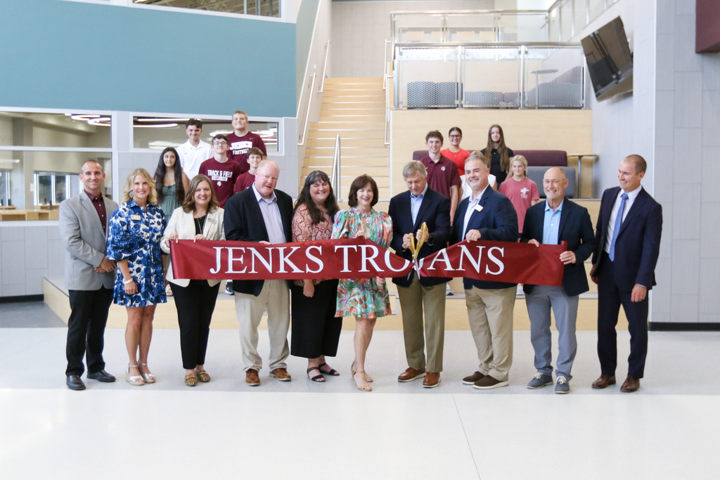 JPS Board of Education members, Superintendent, and Administrators, along with students in the background as the board vice president cuts the ribbon to the freshman academy