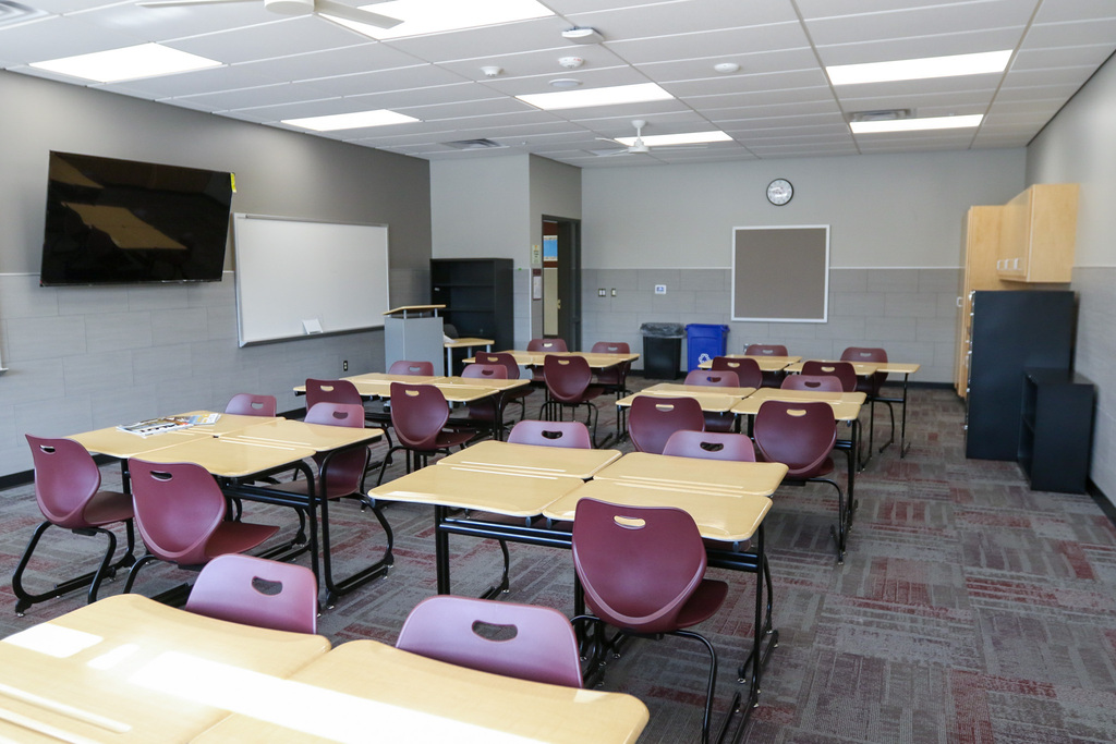 empty classroom with tables and chairs and a whiteboard and tv