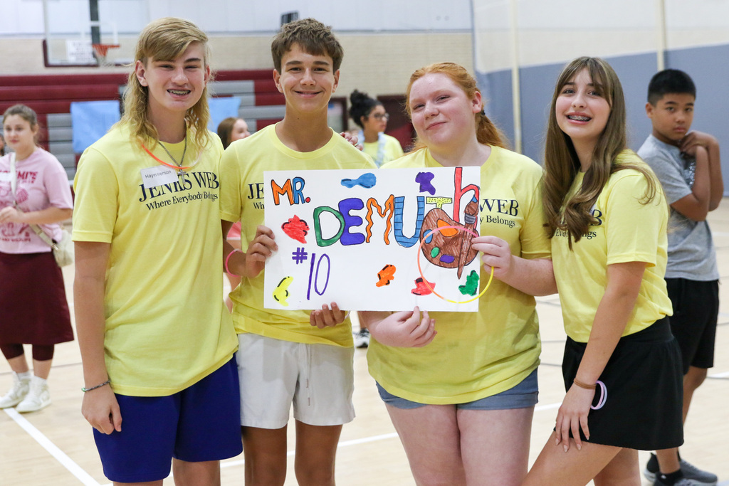 four 8th graders holding up a sign with an advisory teacher sign posing for a photo