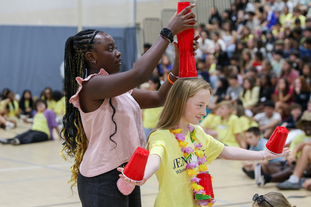 8th grader with red solo cups being stacked on her head by a 7th grader during a game