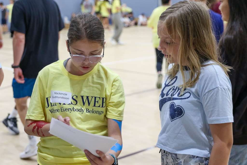 8th grade WEB leader helping a 7th grader find their name tag