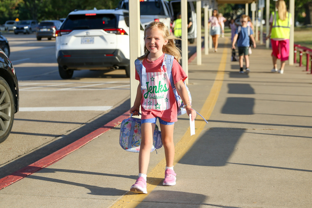 girl walking to the school building with her lunch bag in hand