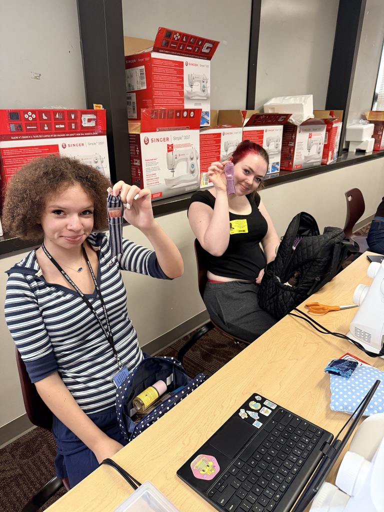 two students showing off their sewing projects