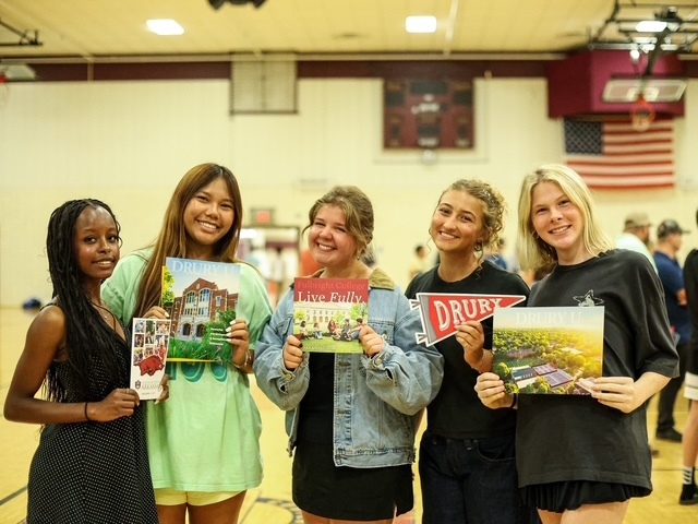 group of 5 girls posing for a photo with college brochures