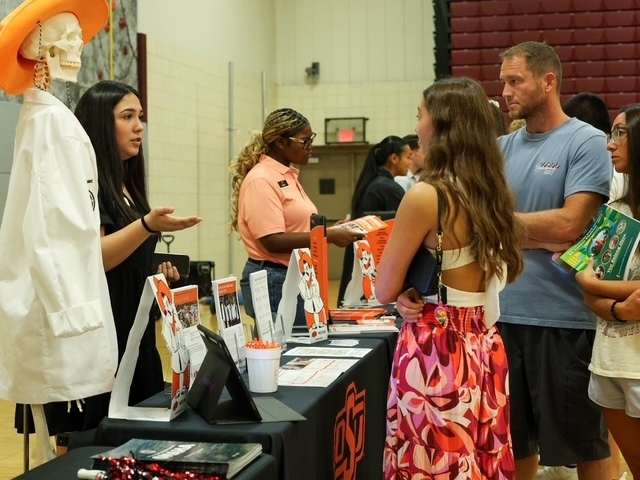high school student listening to a representative from oklahoma state talk at their booth